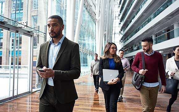 Business professionals walking through building with Microsoft devices
