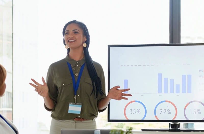 Business women presenting in front of large monitor