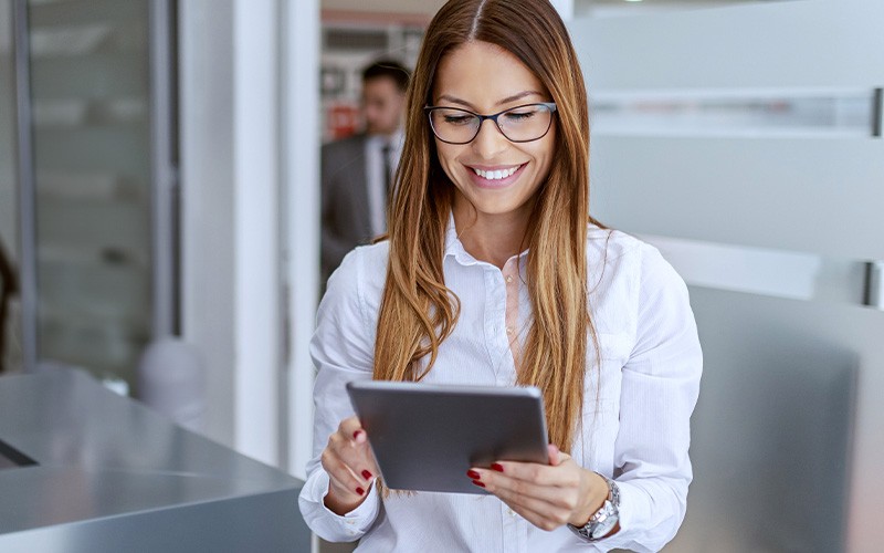 Woman holding tablet while thinking at white board