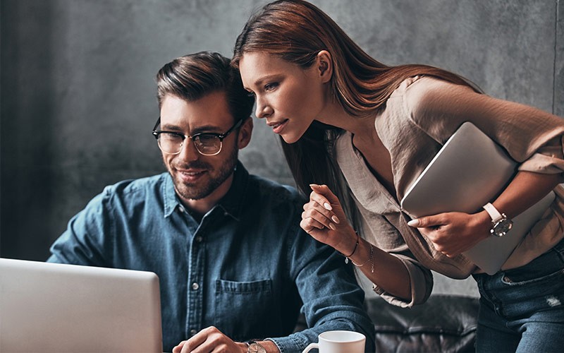 Female assisting a colleague with work on a laptop
