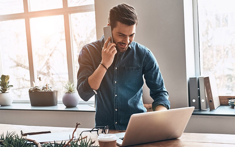 Man talking on the phone while using a laptop