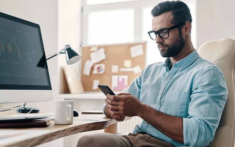 Man checking his phone while sat at a desk